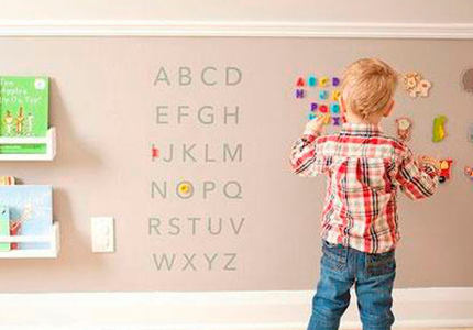 Fotografia de quarto infantil, com criança brincando com a decoração de letras na parede.